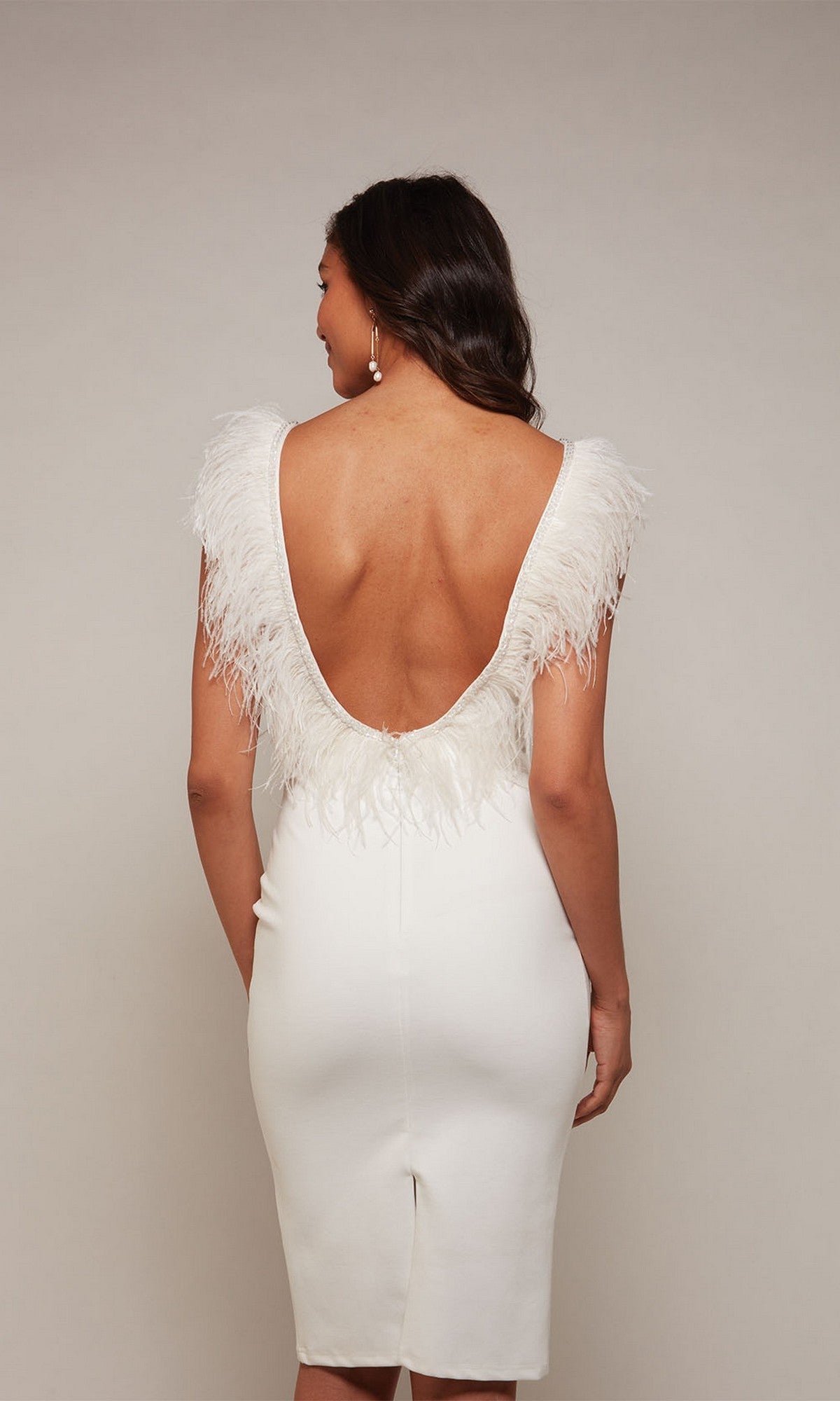 A woman faces away from the camera against a plain light background, wearing the Alyce 70033 knee-length semi-formal dress with feather-accented shoulders and an open back.